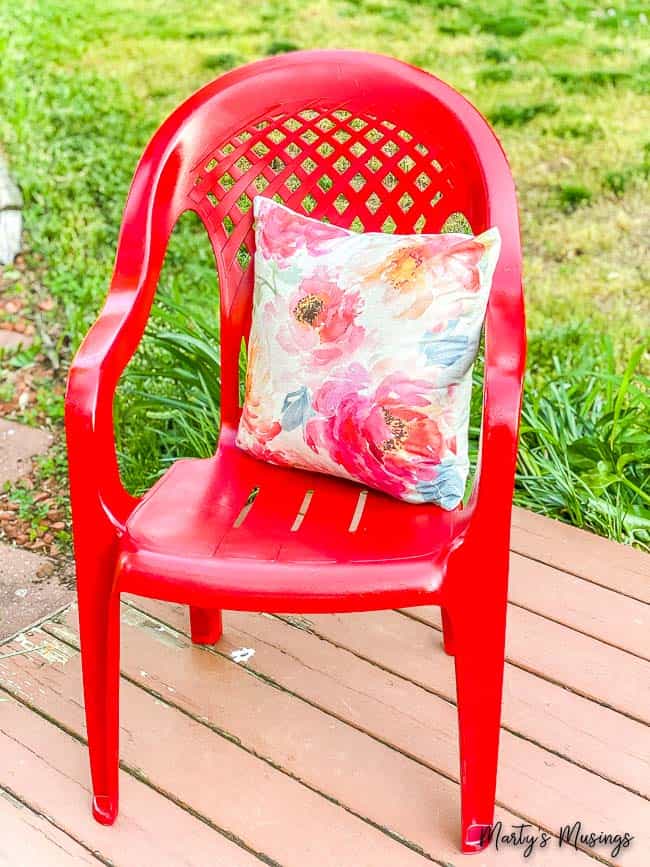 Red glossy plastic chair with floral pillow on deck