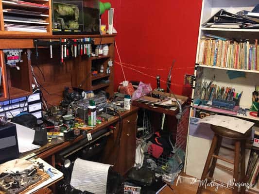 A cluttered desk with a book shelf