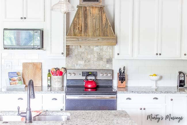 Newly remodeled kitchen with white cabinets, granite countertops and wood vent hood