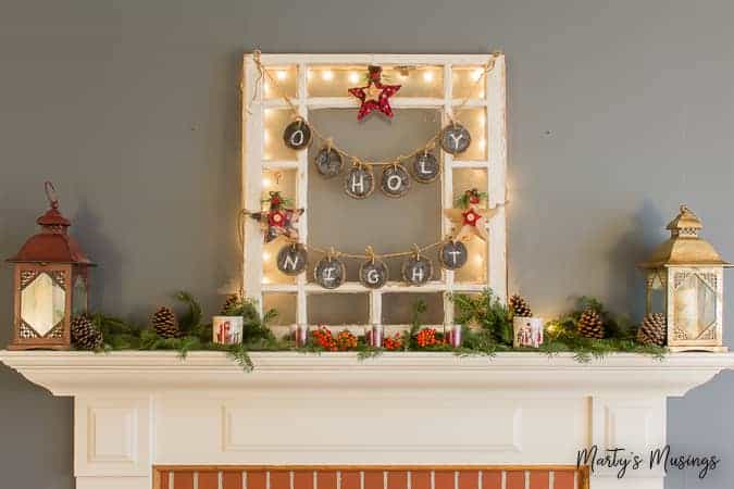 Christmas mantel with greenery and berries and old window with lights