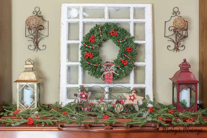 Christmas mantel with old window and wreath hanging with greenery and berries