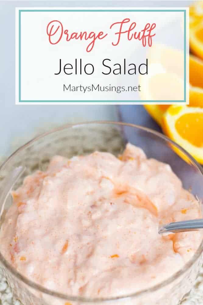 Orange fluff jello salad in glass bowl with fresh oranges
