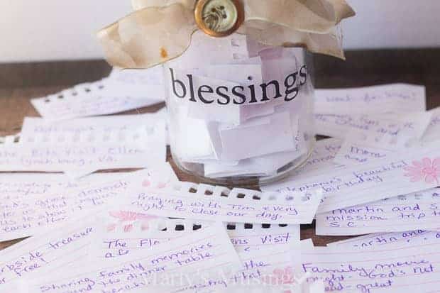 Clear jar with blessings on the outside surrounded by slips of paper