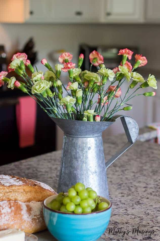 Flowers in tin pitcher on granite countertop