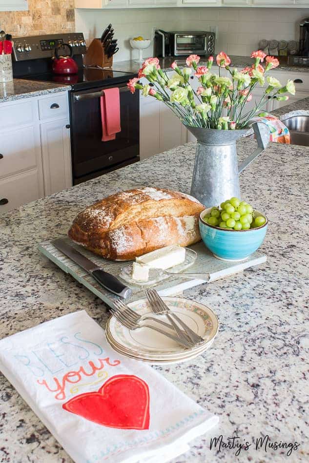 Flowers and bread on cutting board on granite countertop