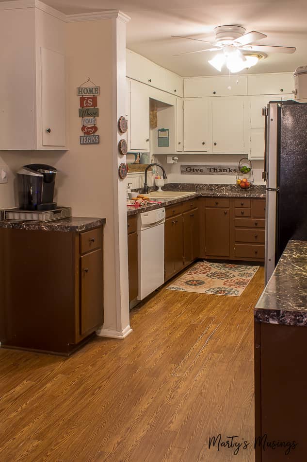 Brown bottom cabinets and white top cabinets in dated ranch style kitchen