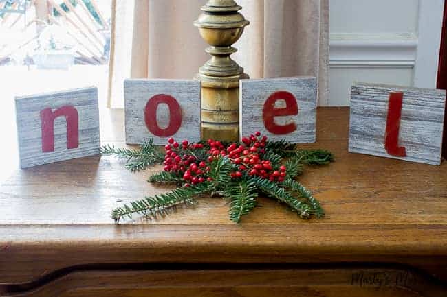 white washed wooden letters with noel on them and greenery and berries