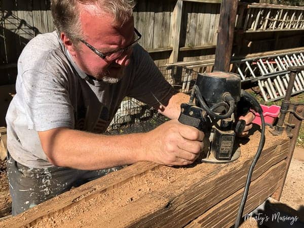 Man cutting out grooves in barn wood for mantel