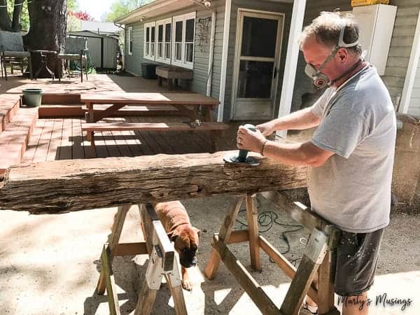 Man with mask sanding barn wood log