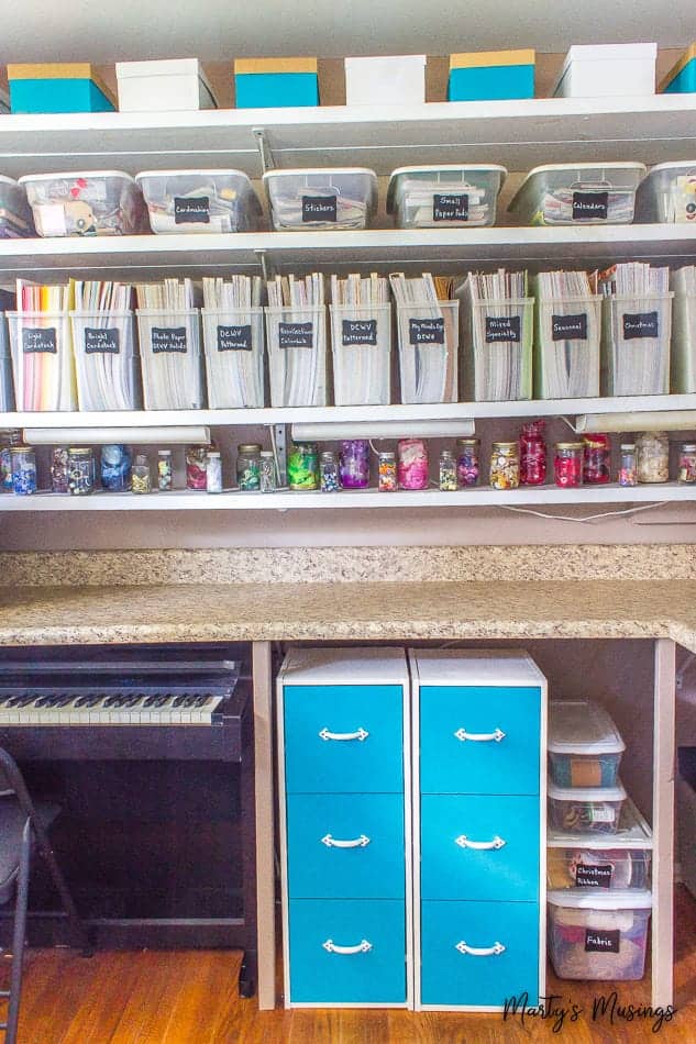 Craft room with binders of scrapbook paper and blue drawers