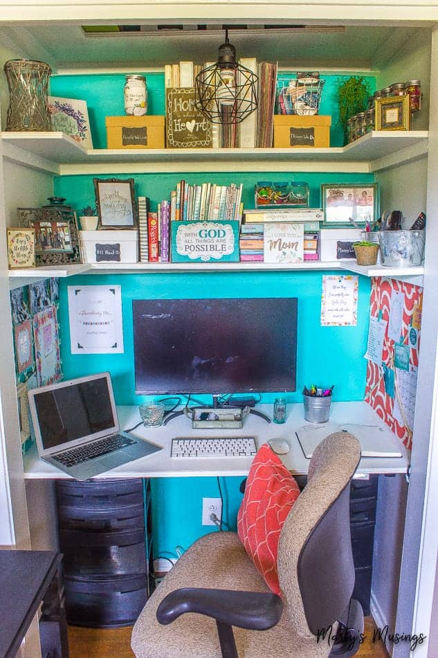 home office in a closet with teal accent wall and shelves