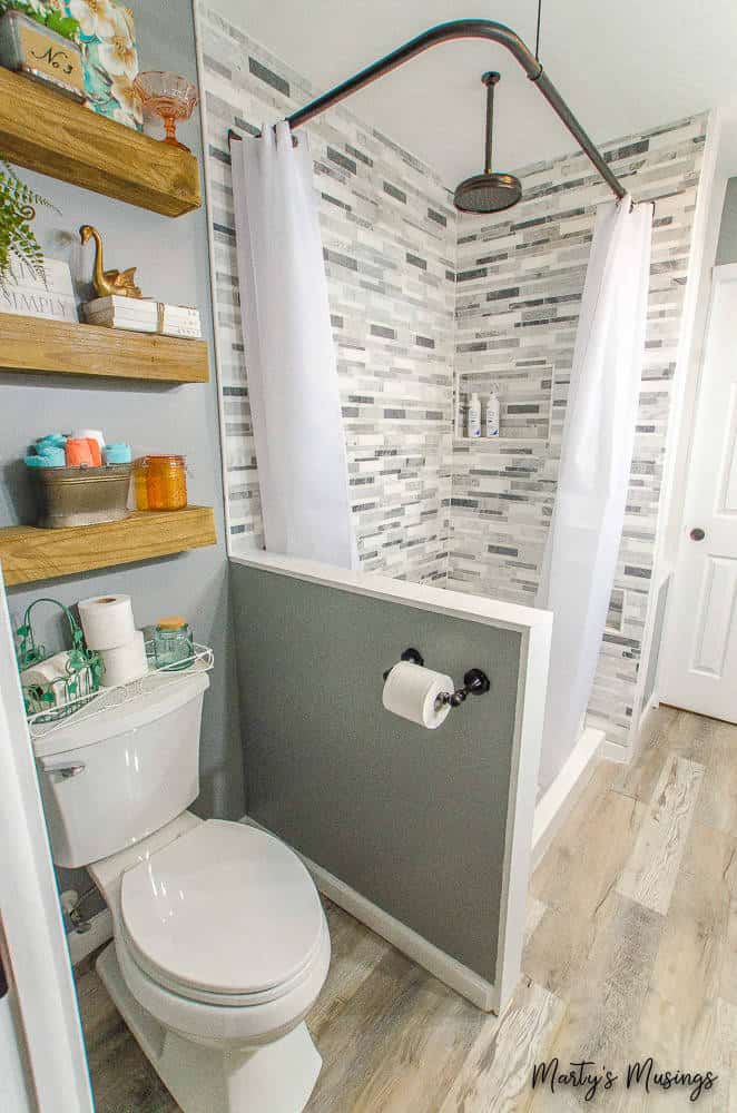 farmhouse bathroom with floating wood shelves and open shower