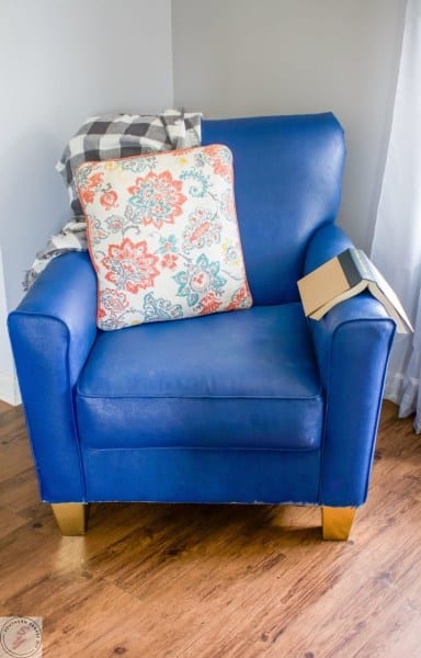 A living room with a blue seat sitting in a chair