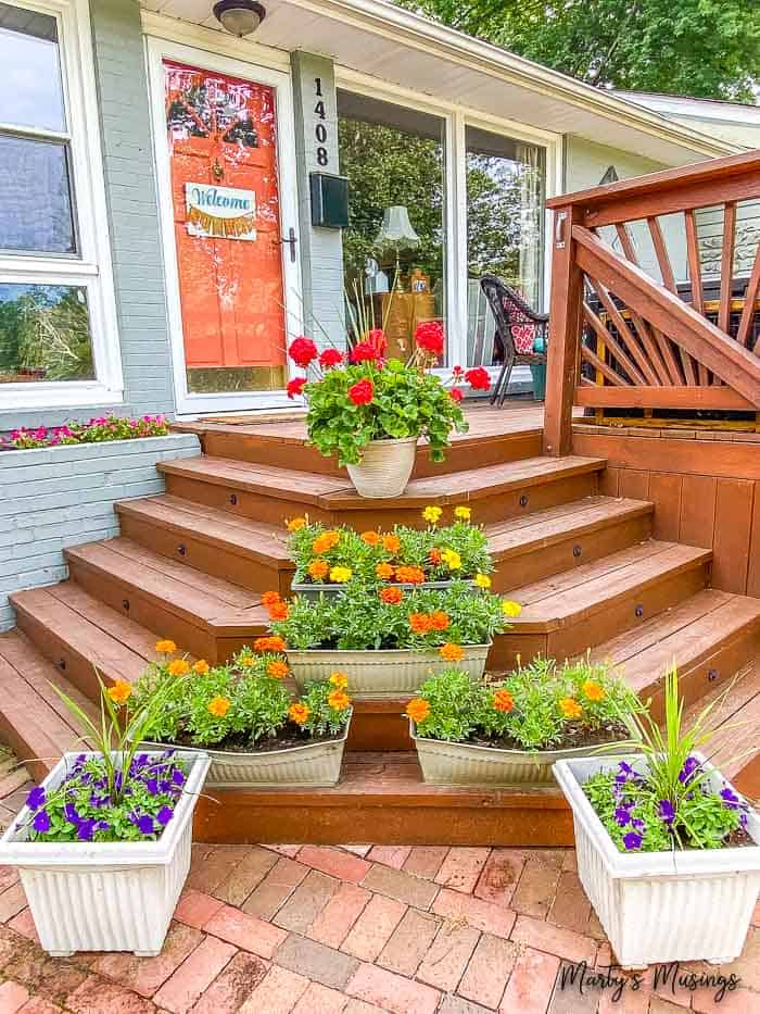 front deck of ranch home decorated with planters full of flowers