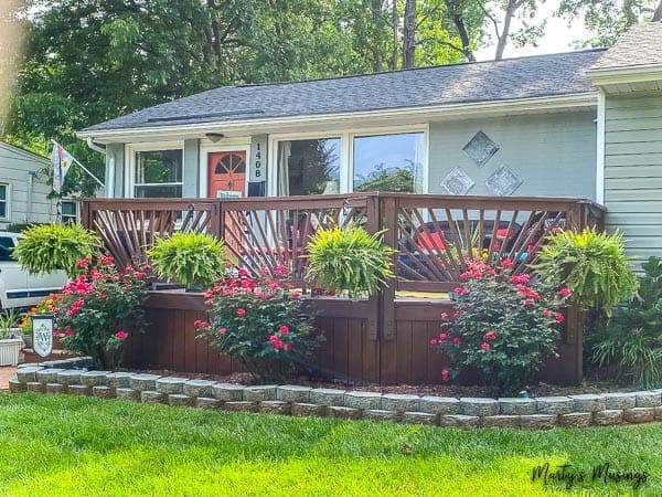 ranch home with front deck decorated with ferns and roses