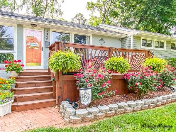 ranch home with large front deck with ferns and roses