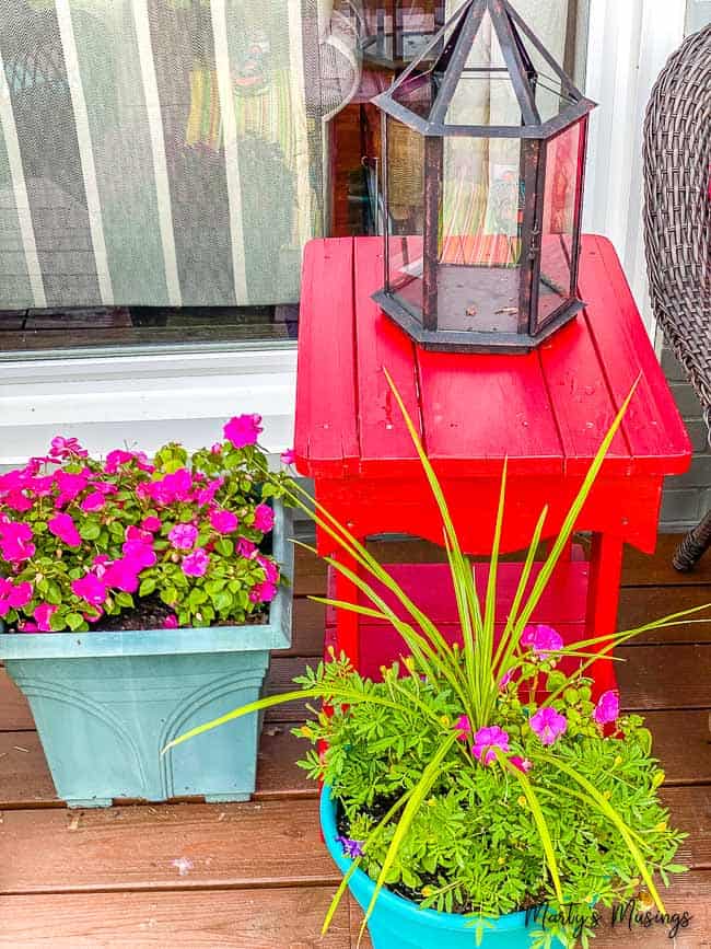 red porch table with planters of flowers