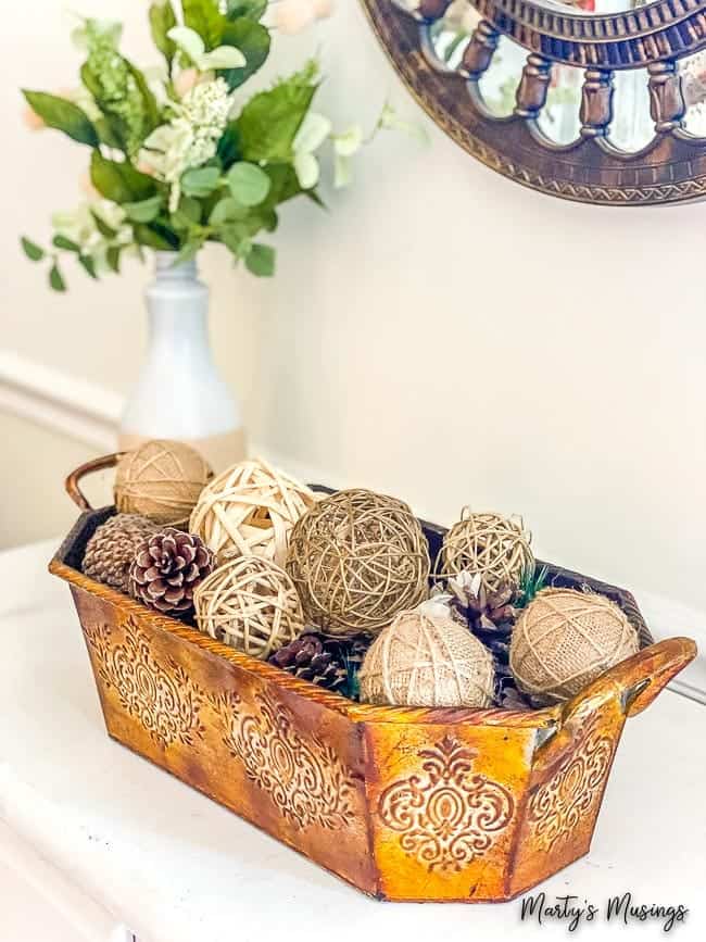 copper container with seasonal elements like pine cones and textured balls