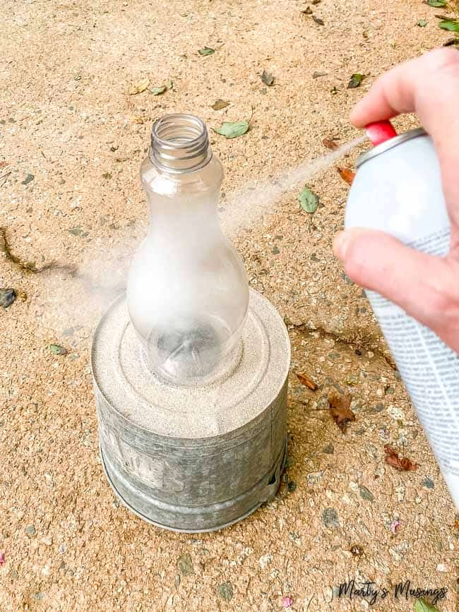 spray paint white a plastic bottle outdoors