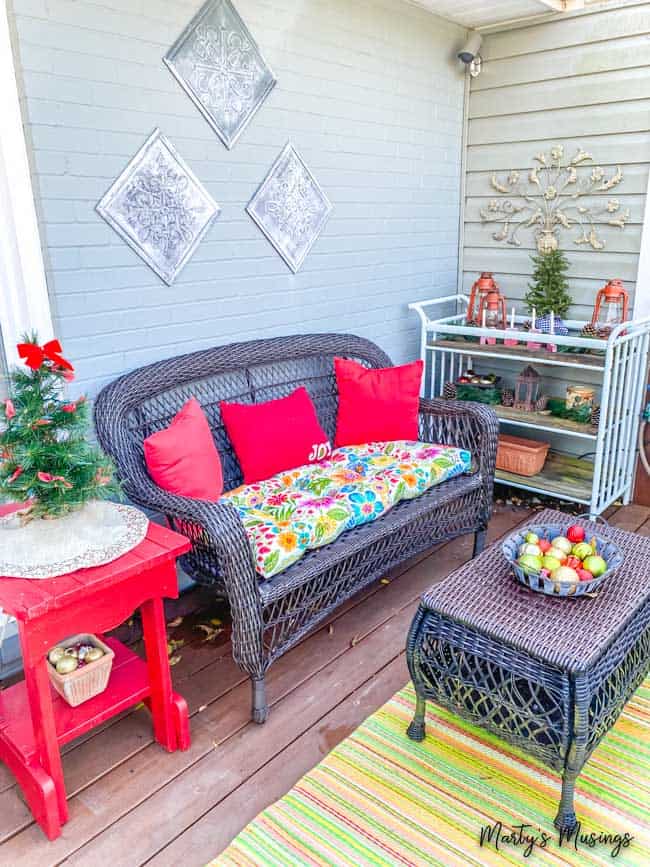 front porch Christmas decorations include red accents with greenery and ornaments