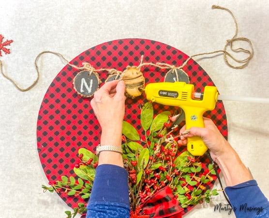 hot glue wood slices onto buffalo plaid hoop wreath