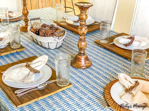 blue sheet used as table runner with wood accents and white china