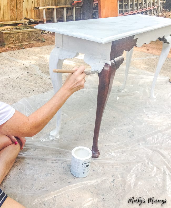 Sofa table being painted with white chalk paint outdoors