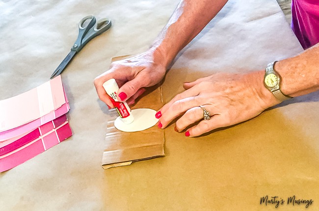 glueing oval onto cardboard with pink paint chips