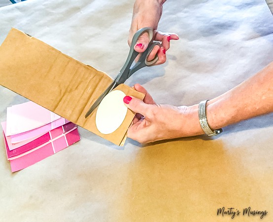 cut out oval from heavy cardboard with pink paint chips on the counter