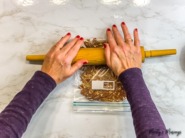 woman using rolling pin to smash pecans