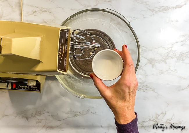 woman pouring vinegar into a vintage mixer