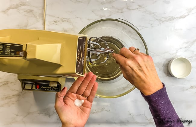 woman sprinkling salt into vintage mixer