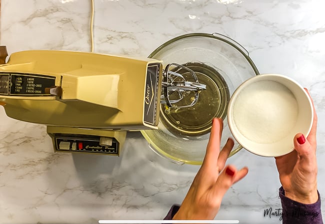 woman pouring sugar into vintage mixing bowl