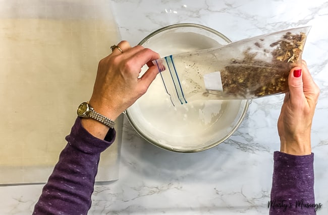 woman pouring crushed nuts into meringue mixture