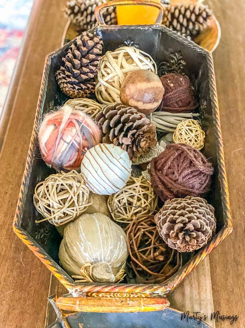 Copper basket filled with pinecones, rustic balls and pumpkins