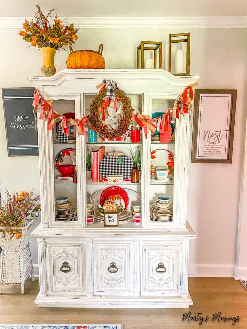 White china hutch filled with cozy fall decor
