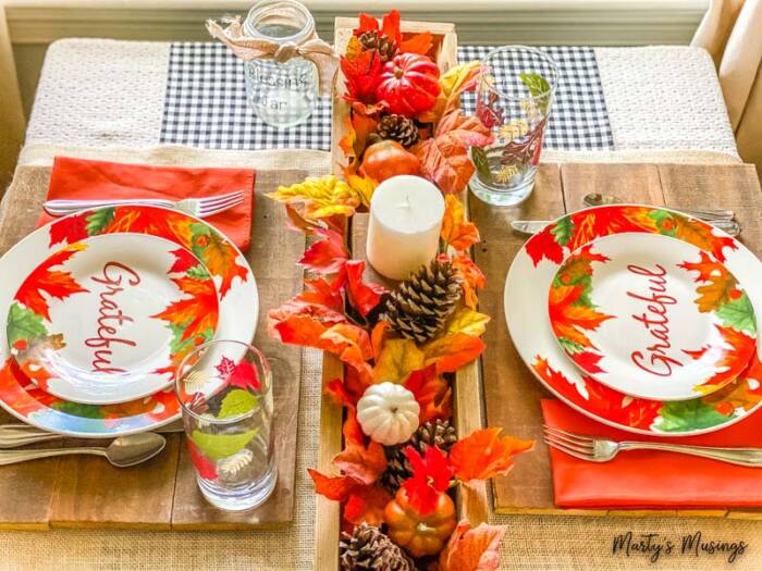 Small table set with grateful fall plates and wooden box filled with leaves and pumpkins