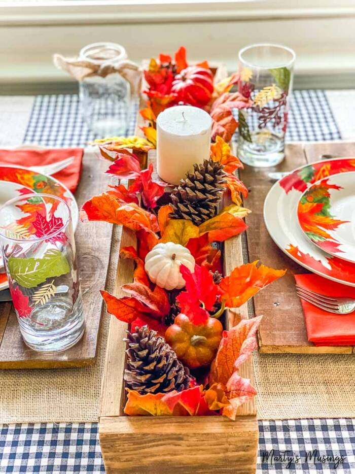 Rustic wooden box filled with fall decor such as pine cones and pumpkins