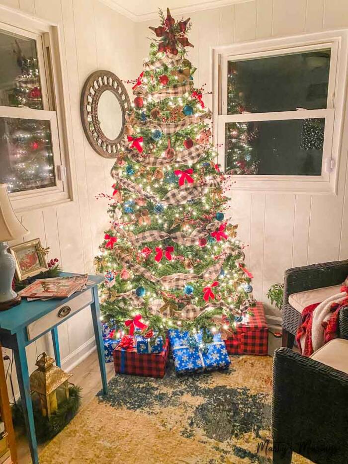 Christmas tree decorated with black plaid ribbon and red bows lit at night