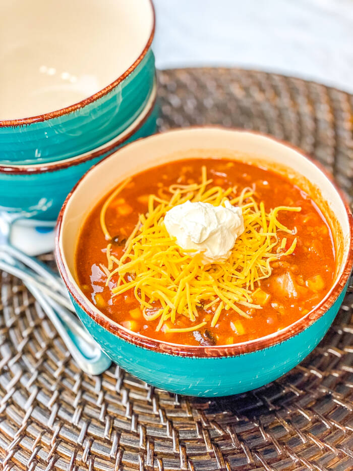 Taco Soup in blue bowl with cheese and sour cream