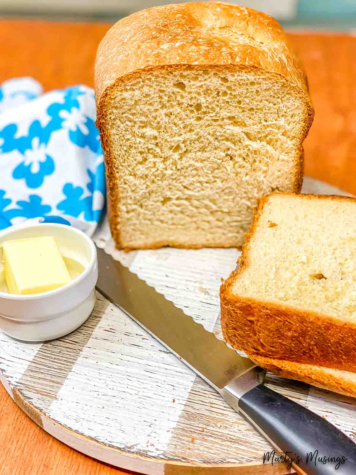 Cut loaf of white bread with knife and butter and blue napkin
