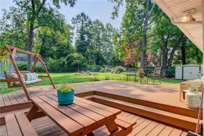 Two level back deck with stained swing set and picnic table