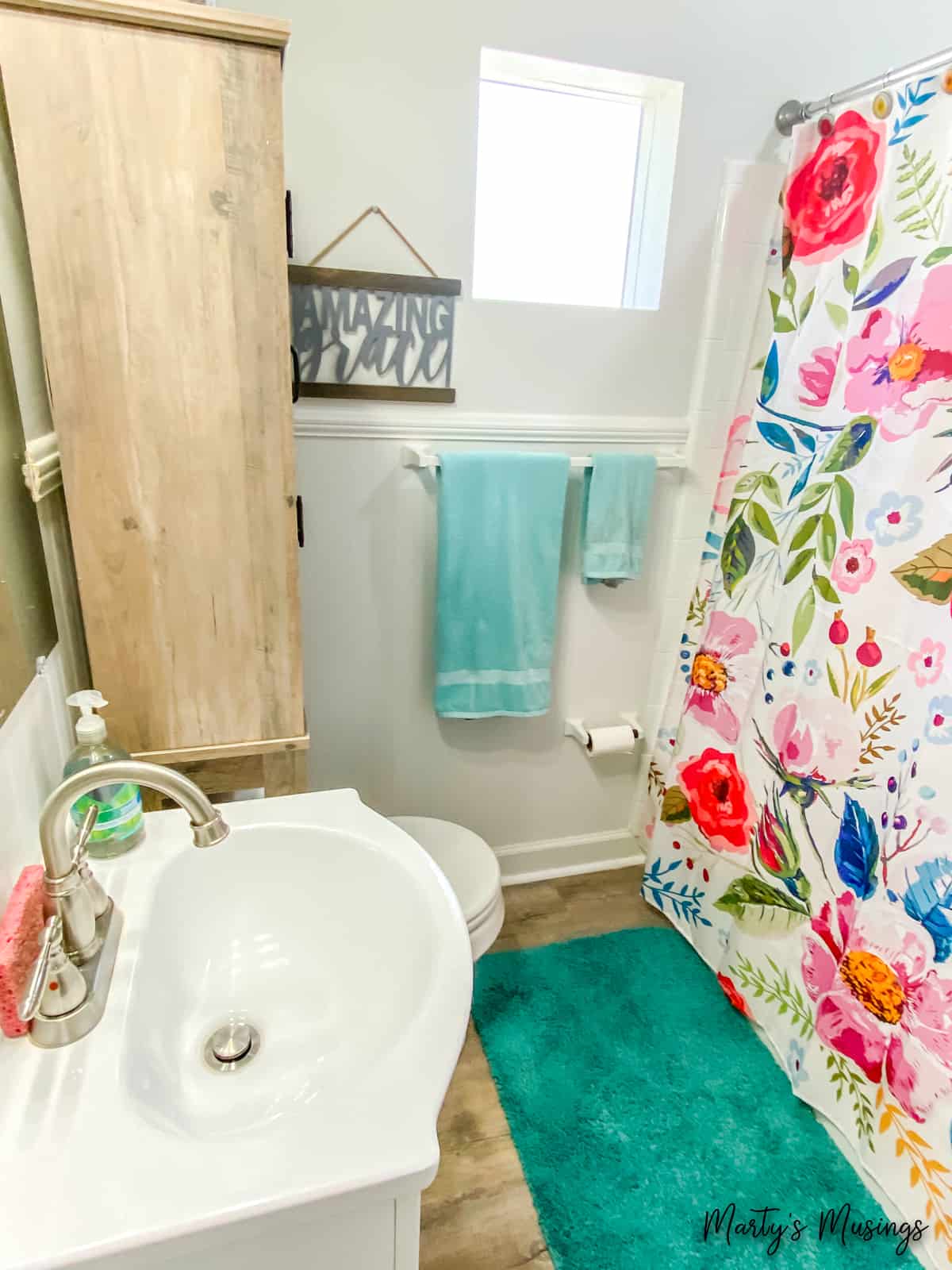 Small bathroom with floral shower curtain and aqua towels