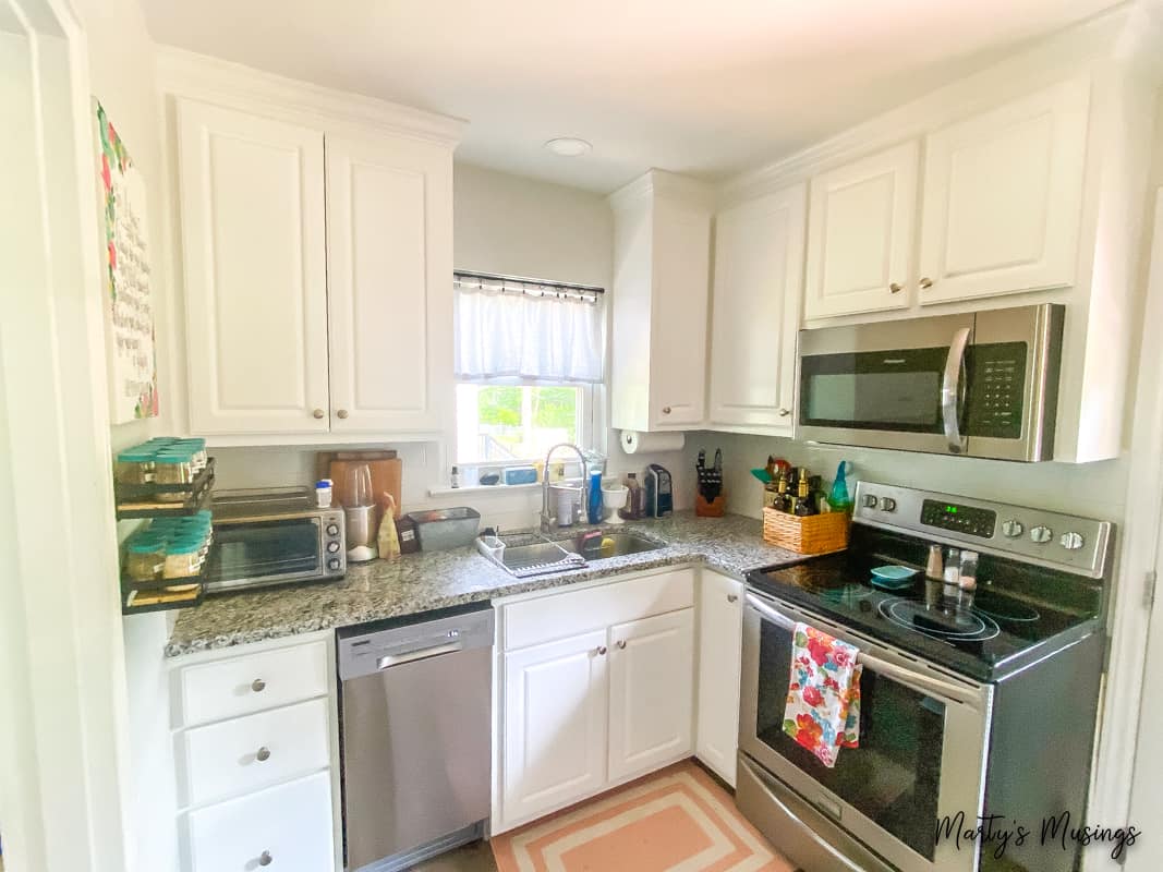 small white kitchen with stainless steel appliances and granite countertops