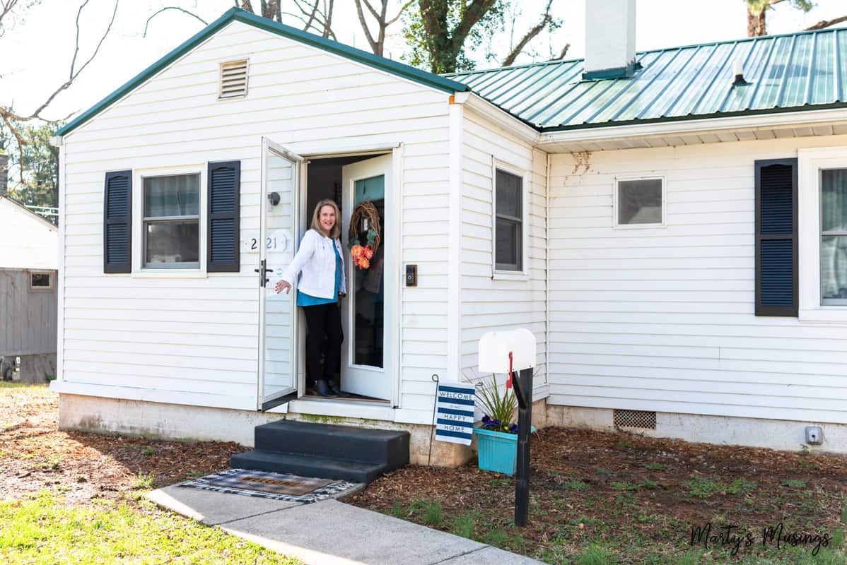 woman holding door open in white cottage