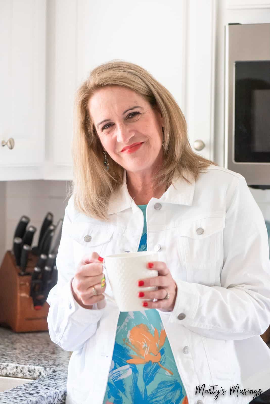 Woman smiling holding coffee mug in kitchen