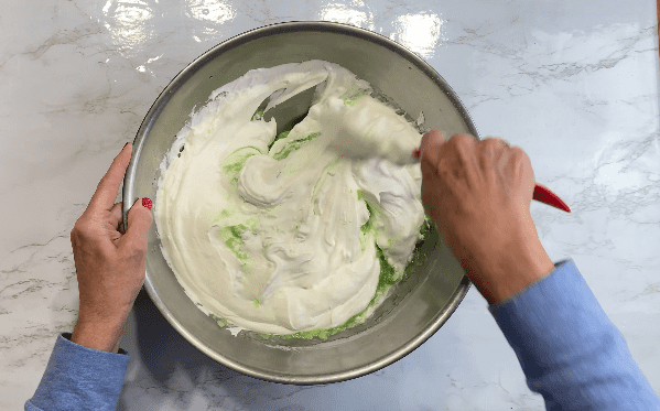 Mixing together whipped topping and green pudding