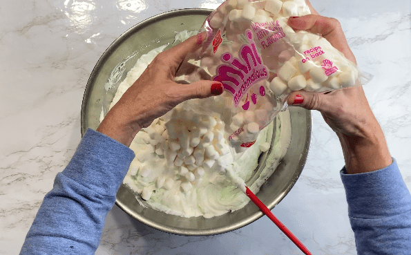 Pouring marshmallows into metal bowl with pudding