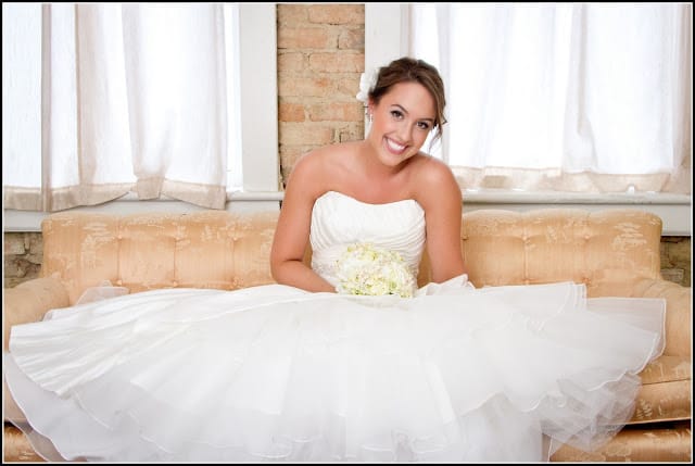 woman sitting on couch in flouncy strapless wedding gown