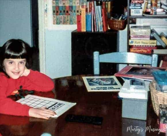 Elementary age girl in red shirt at table doing schoolwork